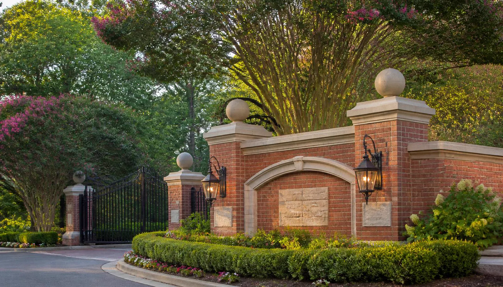 Brick and stone entrance monument with iron gates and crepe myrtles at Austin's Creek