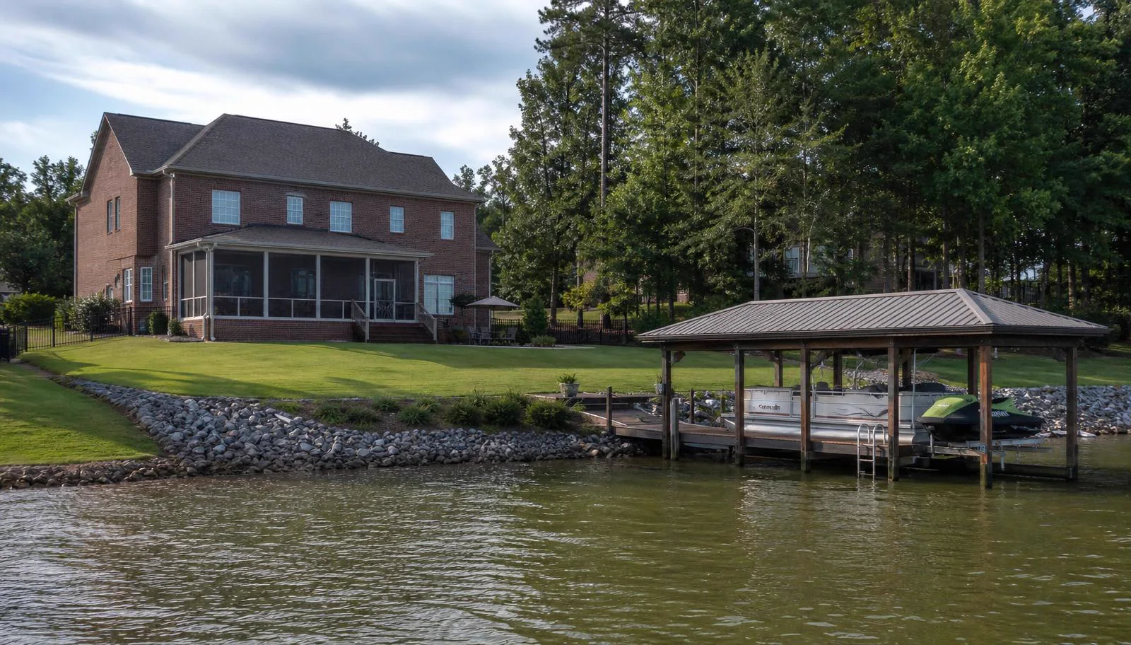 Brick home with screened porch above a riprap Lake Wylie shoreline and covered private boat dock in Crosshaven