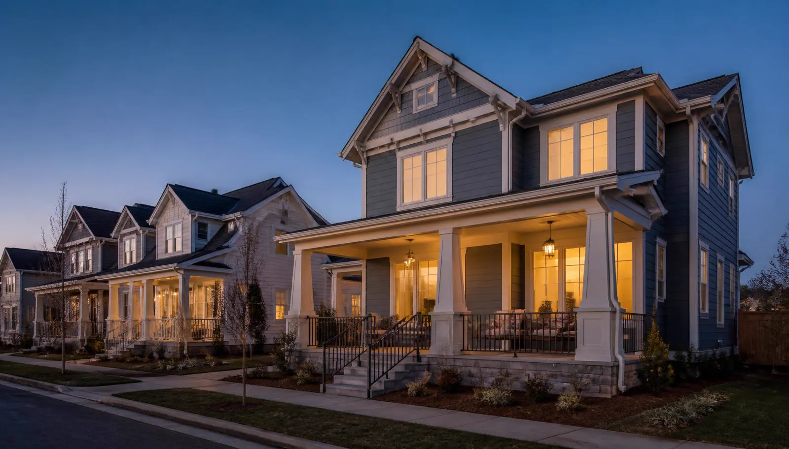 Craftsman homes with lit front porches at blue hour in Lanterns
