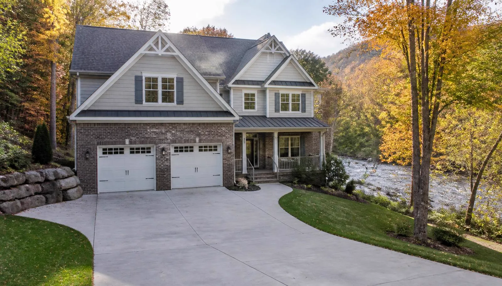 Brick and shingle-sided home on a wooded creek-side lot in autumn in Rusty Creek